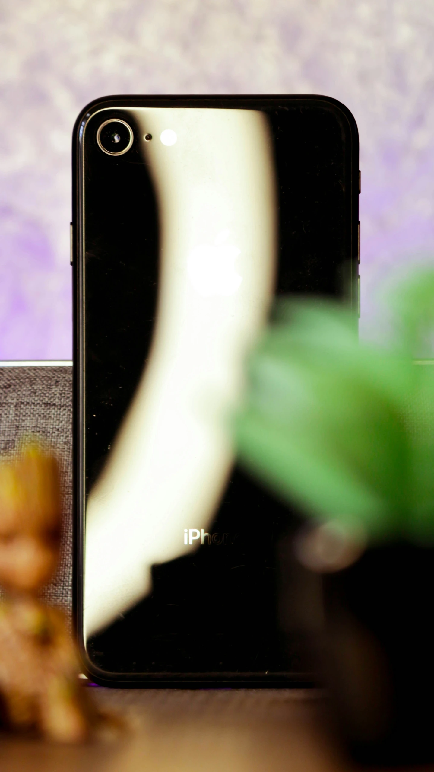 an iphone sitting on a table next to a potted plant