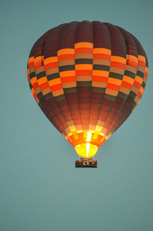 a  air balloon glows orange and red while flying through the sky