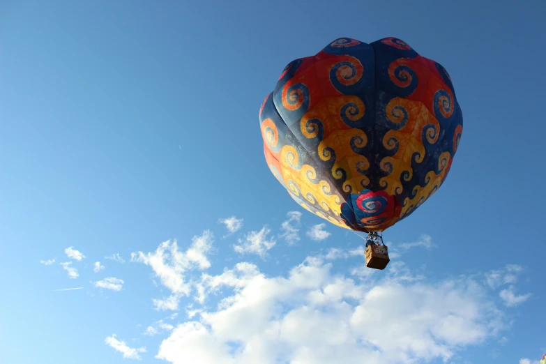 a large colorful balloon flying through a cloudy sky