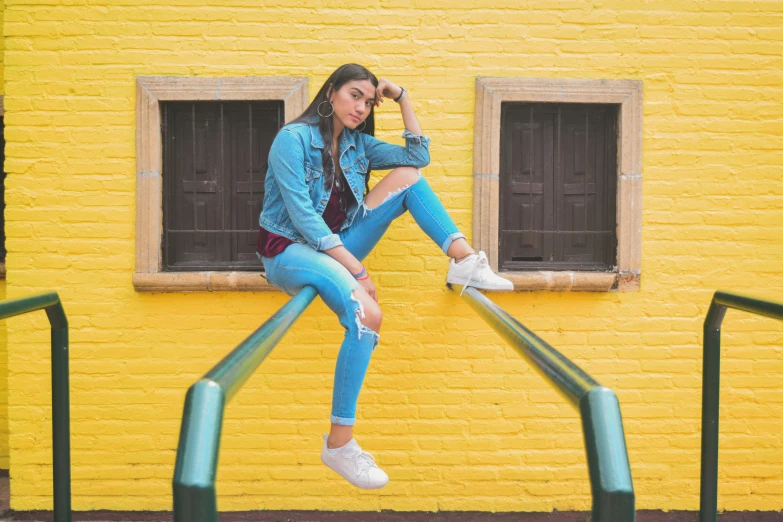 a young woman posing on some rails in front of a yellow building