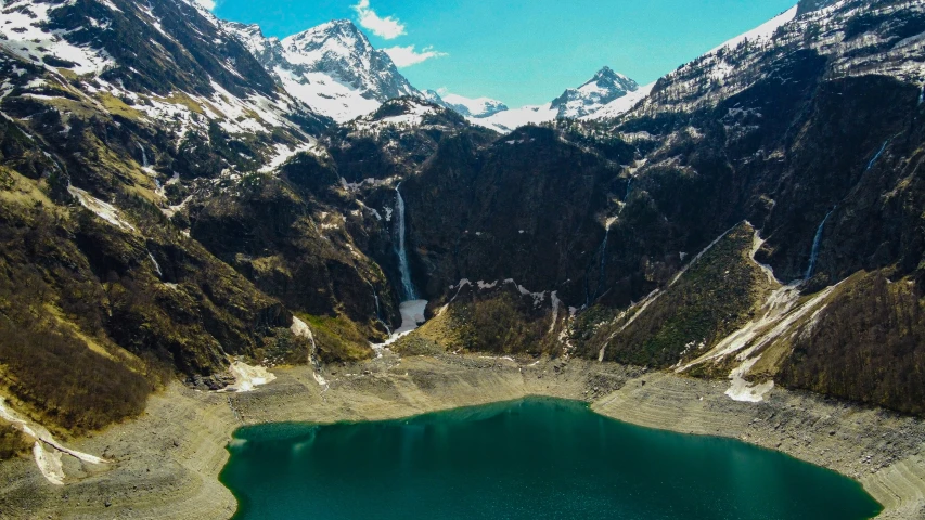 an aerial po of a mountain lake near to a waterfall