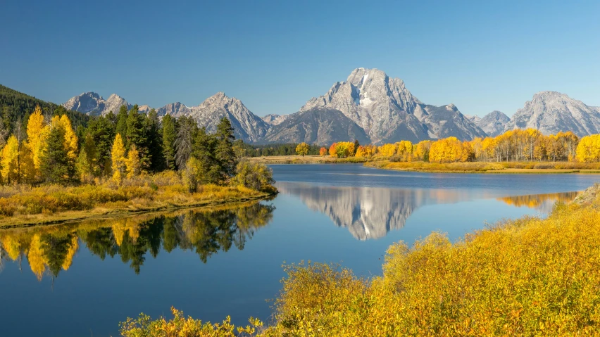 the mountains are reflecting in a body of water