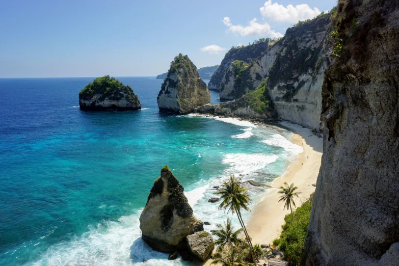 a beach with clear blue water and two rock formations