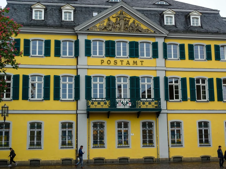 people stand outside of a yellow and green building