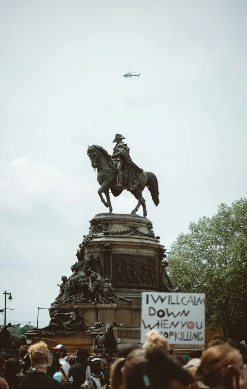 a large crowd of people standing around a statue