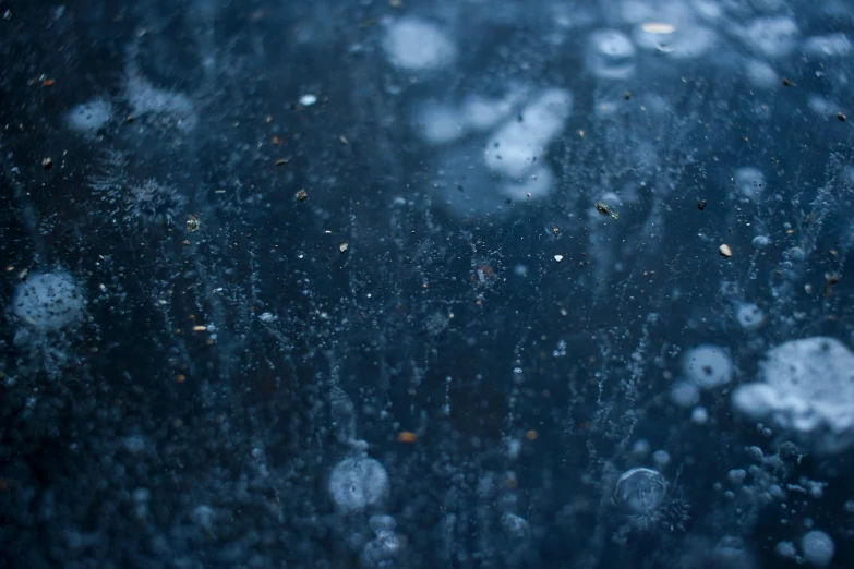 drops of water that appear to be falling from a rain streaked window