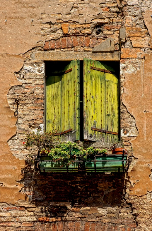 an old window with green shutters and flowers on a brick wall