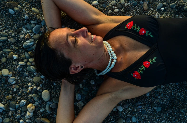 a young woman is lying on some rocks and gravel