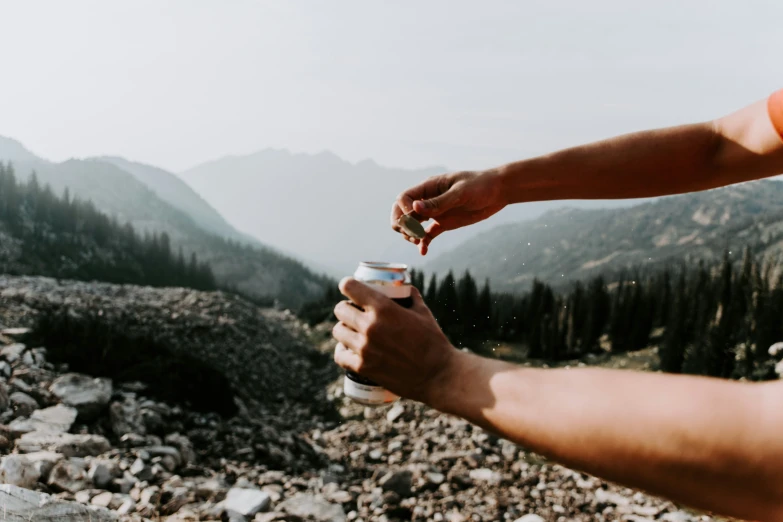 two hands holding coffee cups overlooking a mountainous view