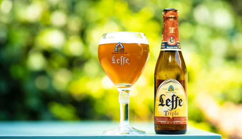 a close up of an opened beer bottle next to a glass filled with beer