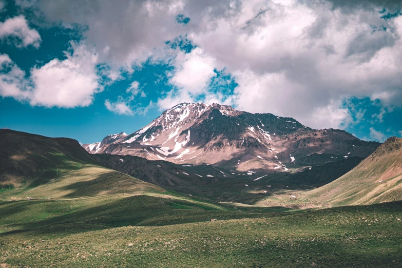 the high mountain range on the plains is covered in a cloud