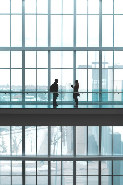 two people are walking on the bridge in a city