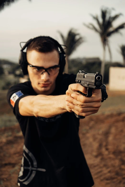 a man with headphones and glasses pointing a gun at the camera