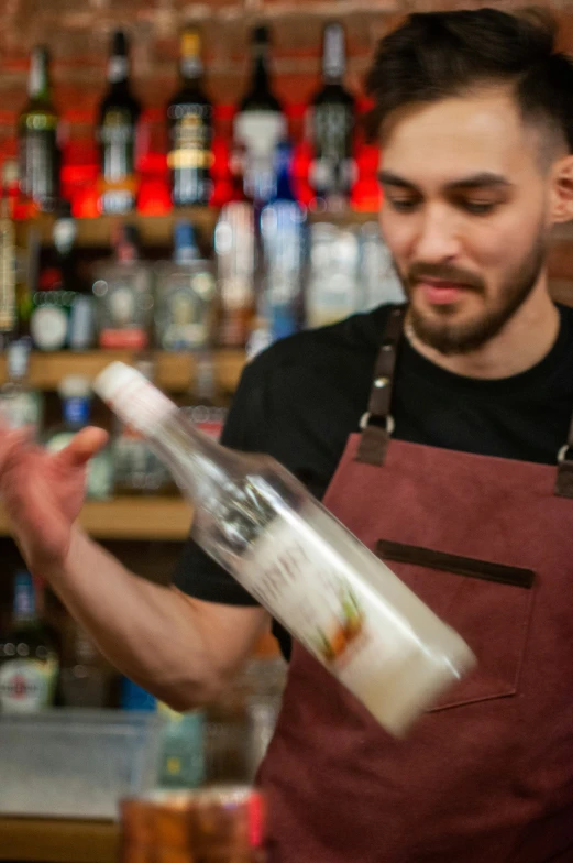 a bartender holding a bottle in one hand and a glass of wine in another