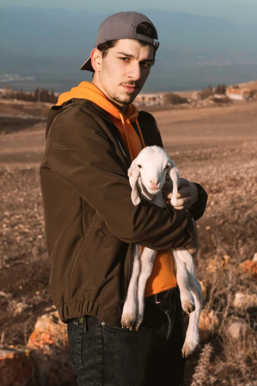 a young man is holding a small lamb in his hands