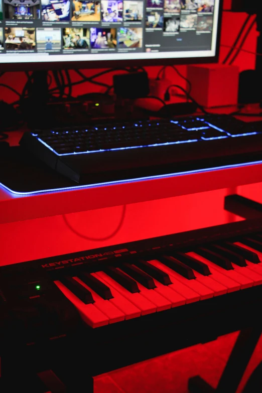 an electronic keyboard lit up with red lights in front of a monitor