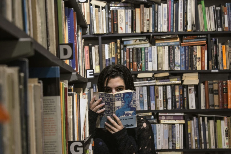 person standing in front of a bookcase reading a book