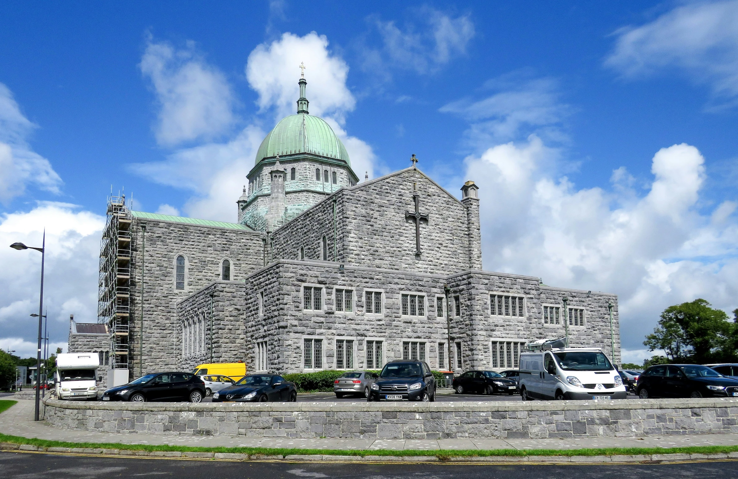 large building with dome and spire sitting behind some trees