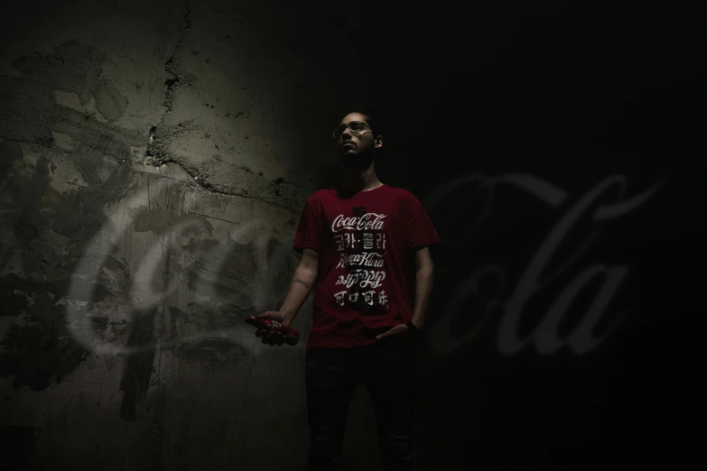 man in red shirt holding cell phone in dark room