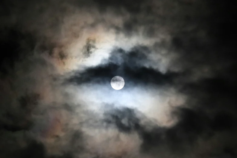 a full moon seen through some dark clouds