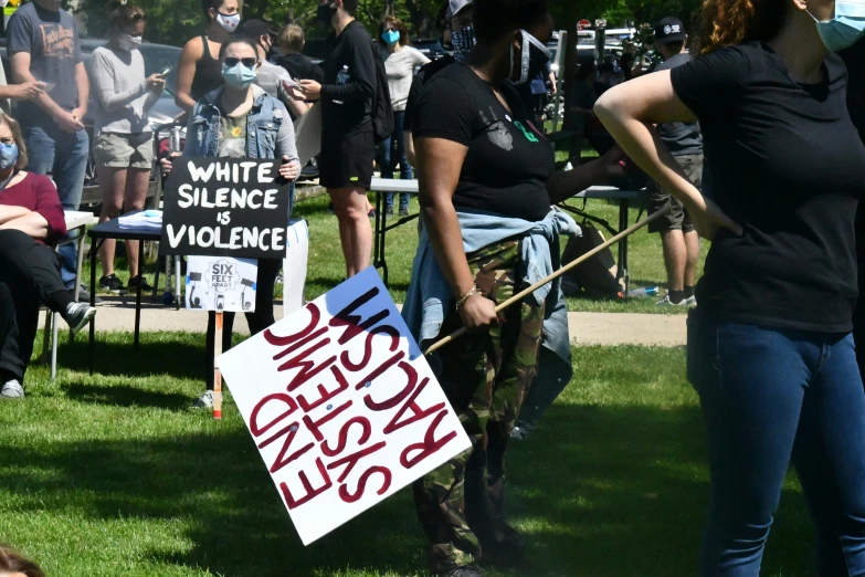 people holding protest signs on the grass in front of the group