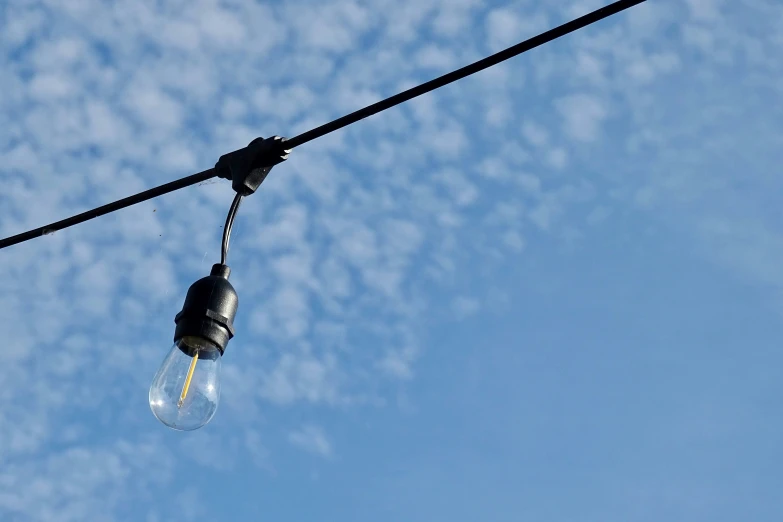 one light bulb is on a wire with a clear blue sky behind it