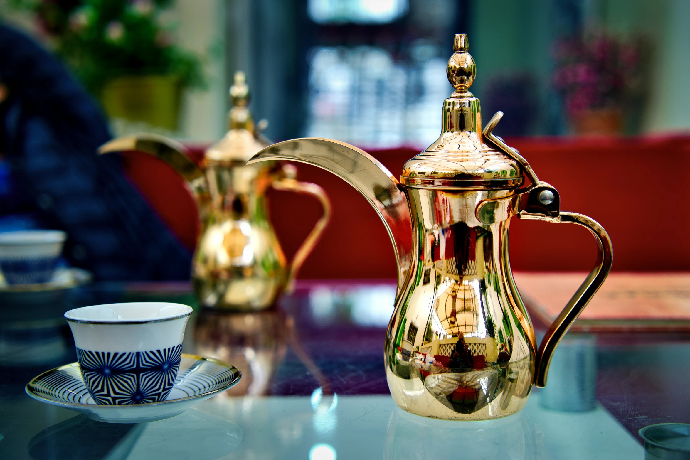 an ornate pitcher and a cup sit on a counter