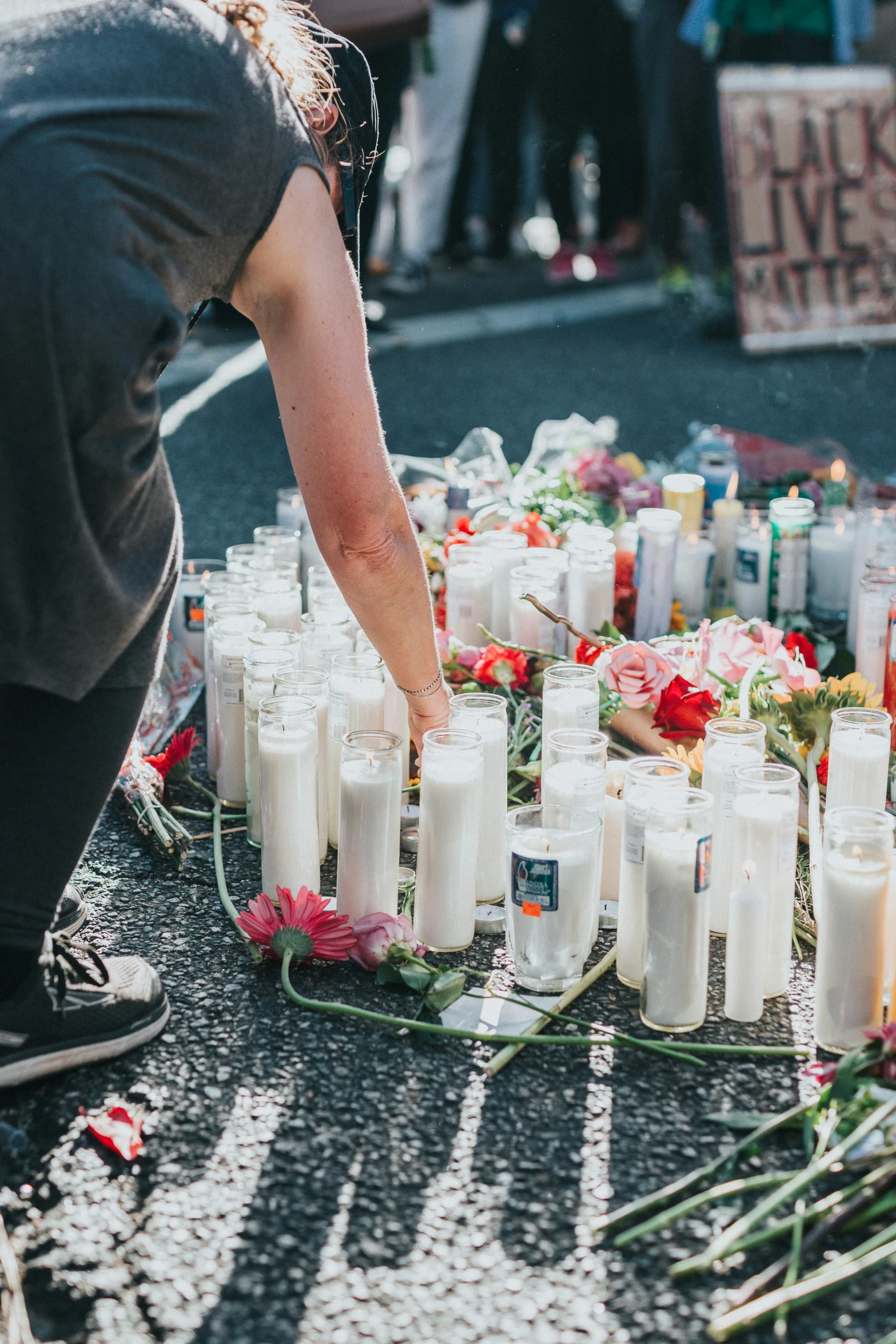 a woman placing candles on a tray for a memorial event