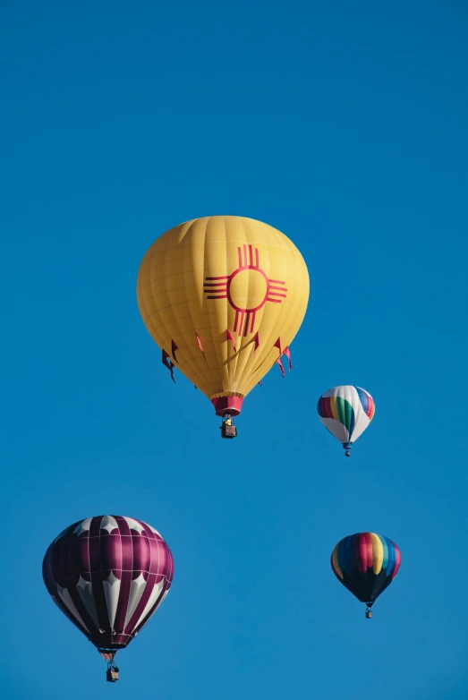 four  air balloons fly through a blue sky