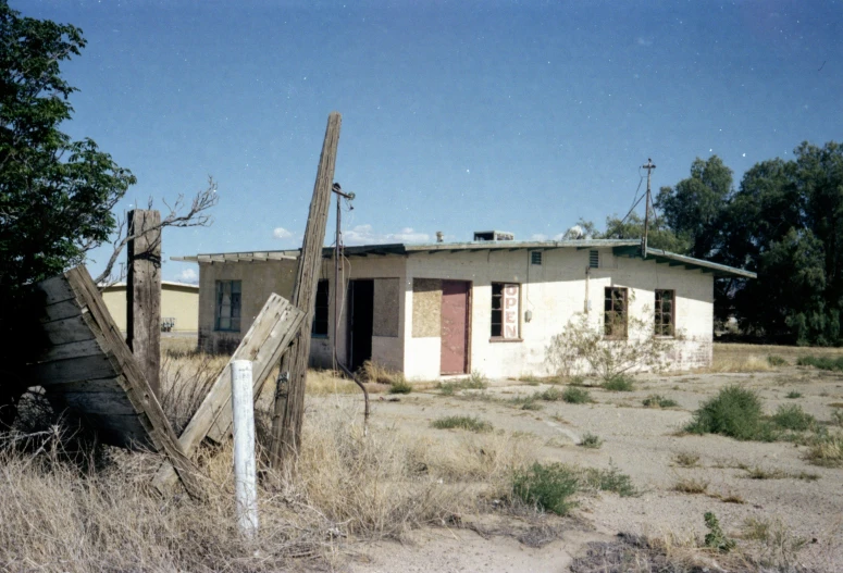 an abandoned white building sits in an overgrown field