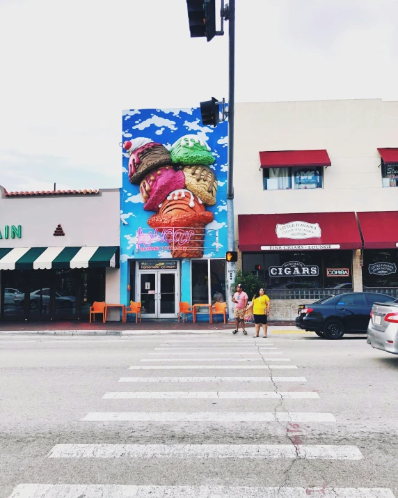 two people walking across the street next to shops