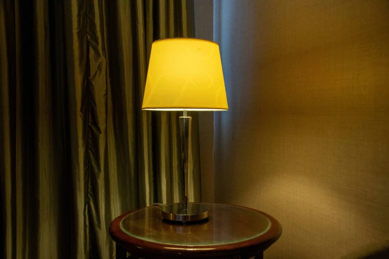 a table with a lamp on it next to a curtained wall