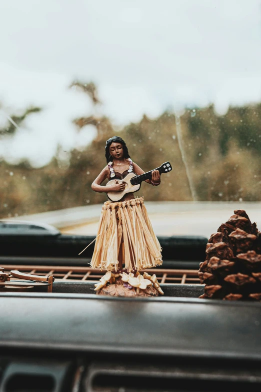 woman in hawaiian dress on truck holding a guitar