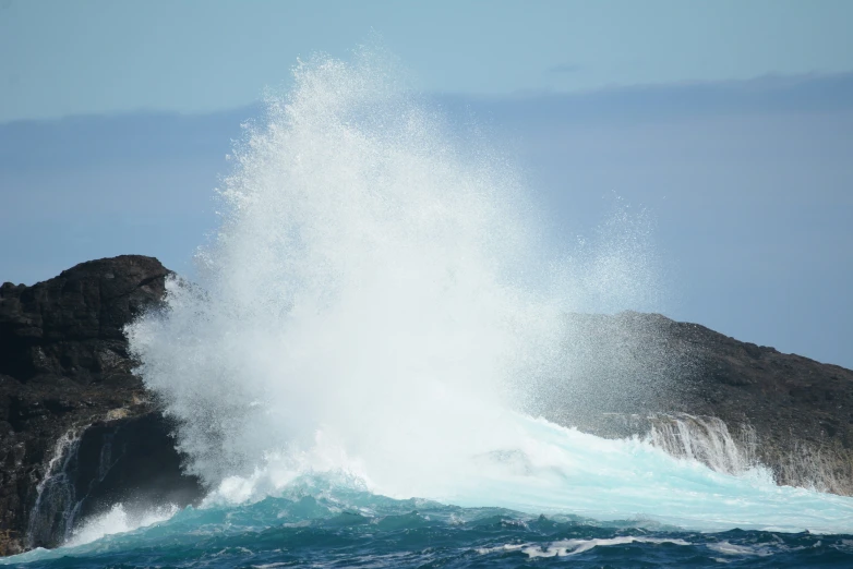 a big wave crashing into the shore by some rocks