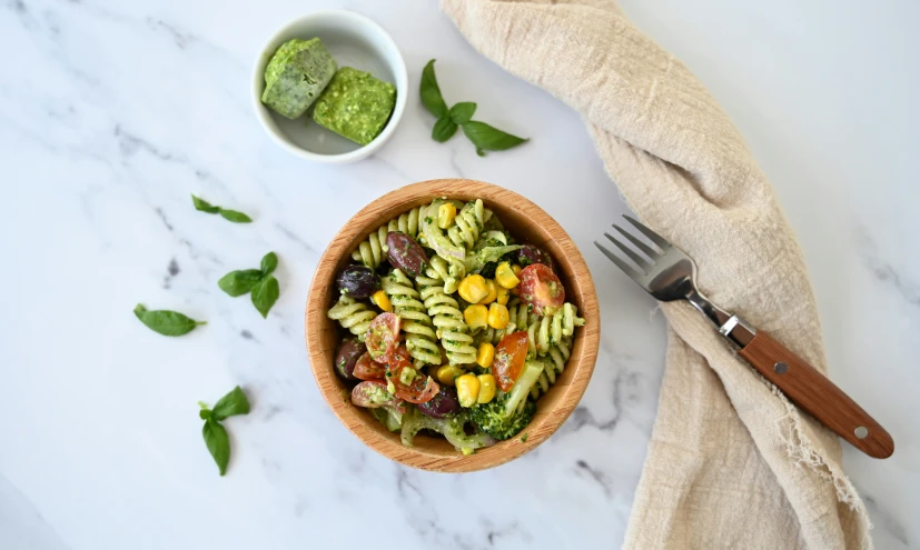 a bowl of pasta salad is shown next to two bowls of pesto, lemon, and chives