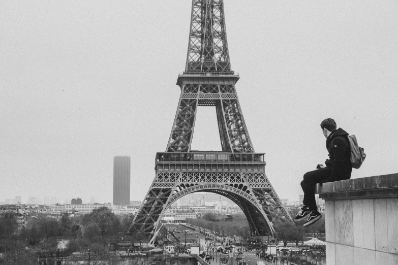 a man sitting on a wall next to the eiffel tower