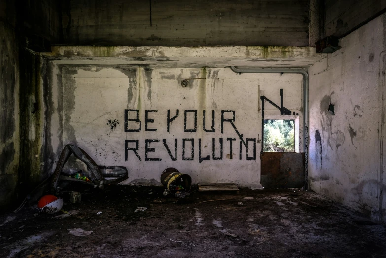 graffiti on a white wall reads be your revolution