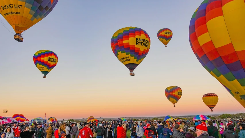 a large crowd of people watch  air balloons