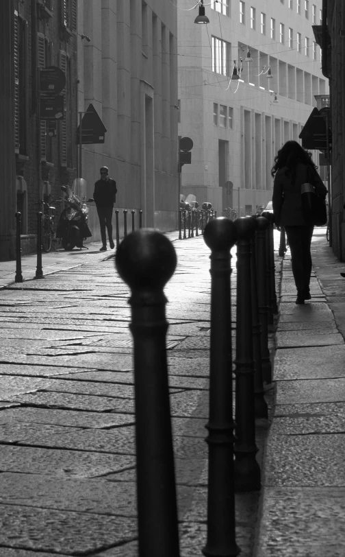 people on a city street next to poles and the sidewalk