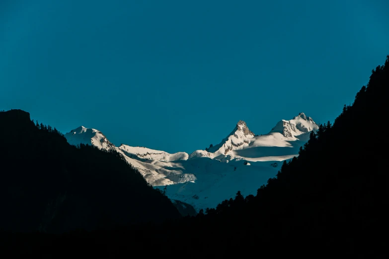 the view of a mountain range from below, under a blue sky