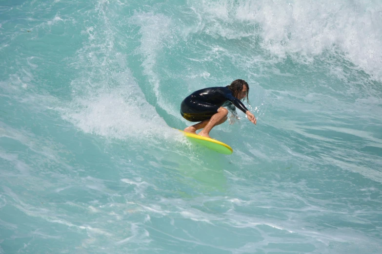 a surfer kneels down while surfing the waves