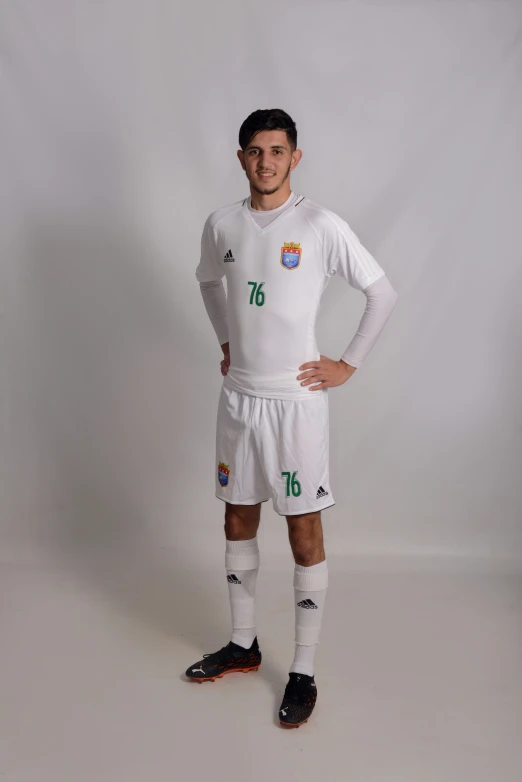 a soccer player poses for a po with his hands on his hips