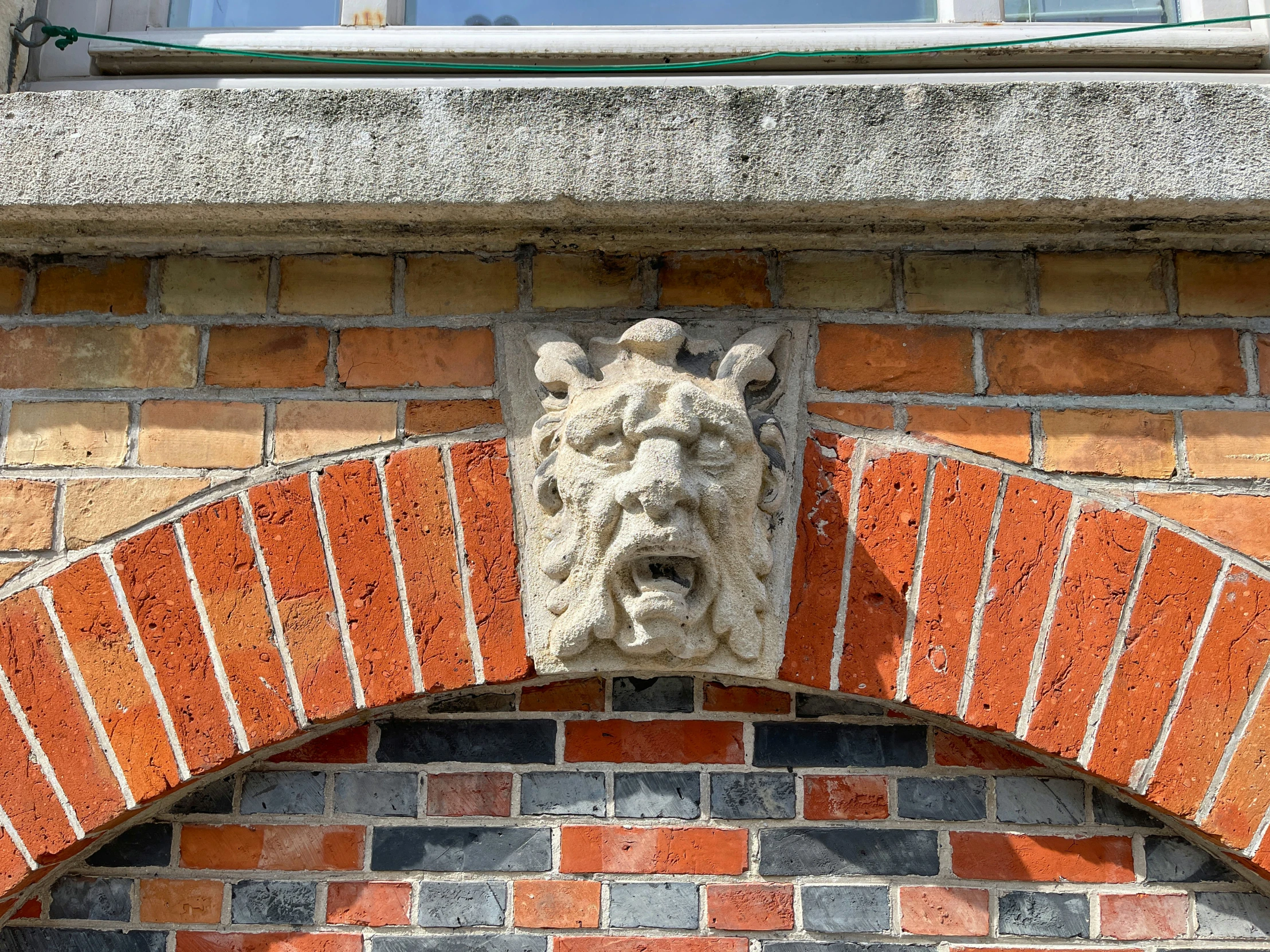 an elaborate brick building with gargoyle face above the door