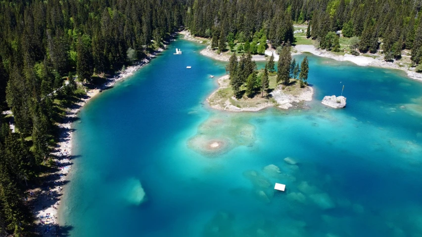 an aerial view of a turquoise colored lake with clear water and trees