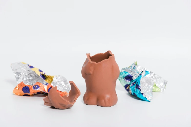 three chocolate sculptures in brown containers on white surface