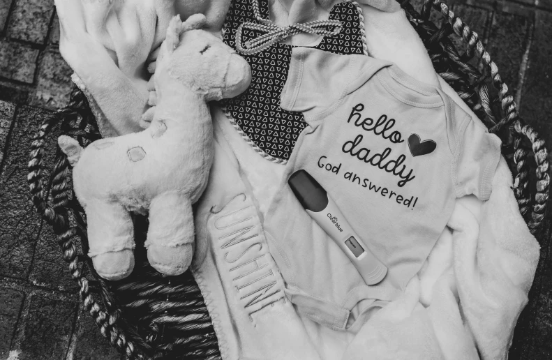 an infant's clothing and baby toy lie in a basket