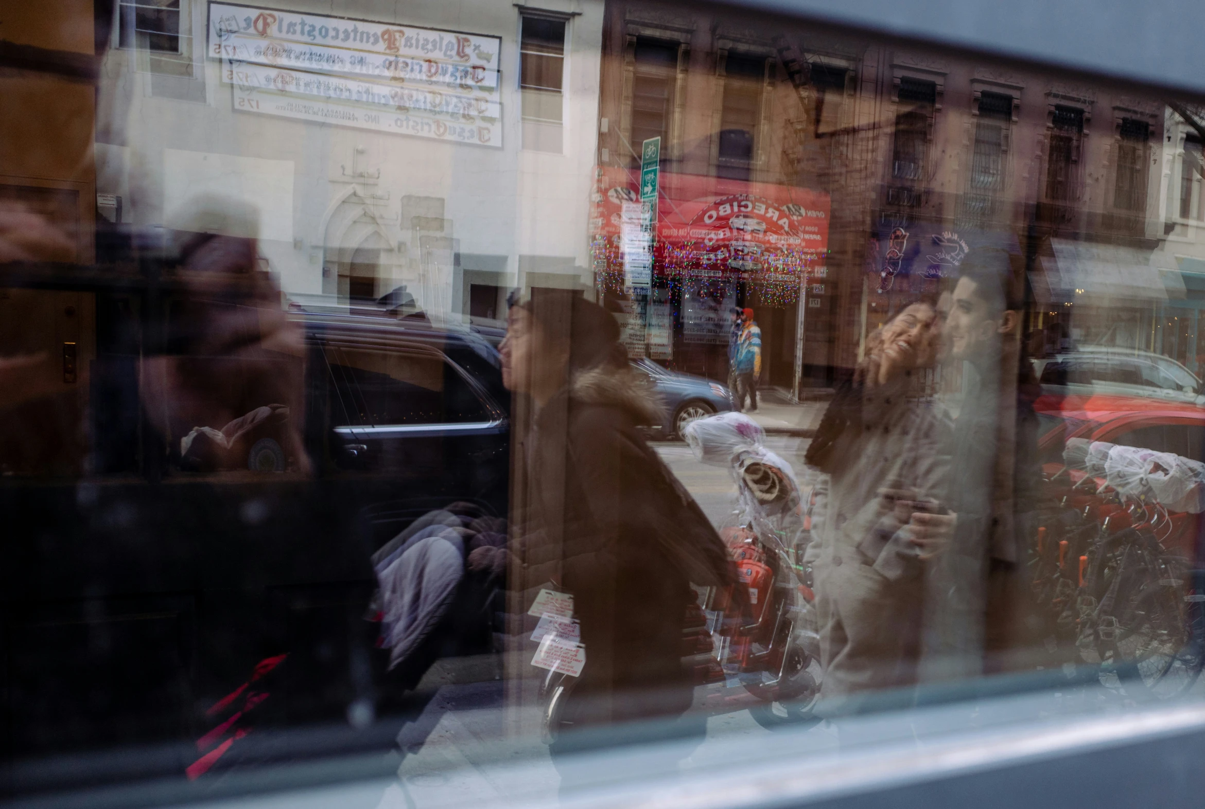 reflection of people in window of building, in a city