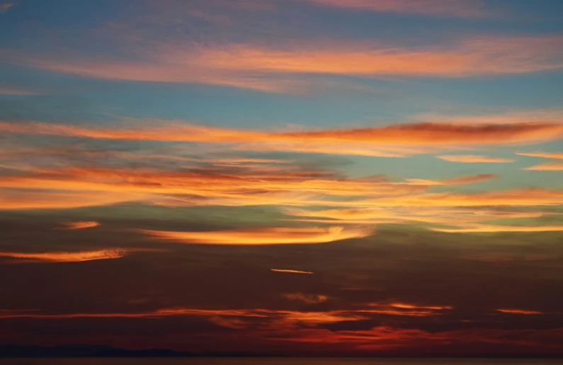 a sunset is seen in the distance as a boat is out on the water