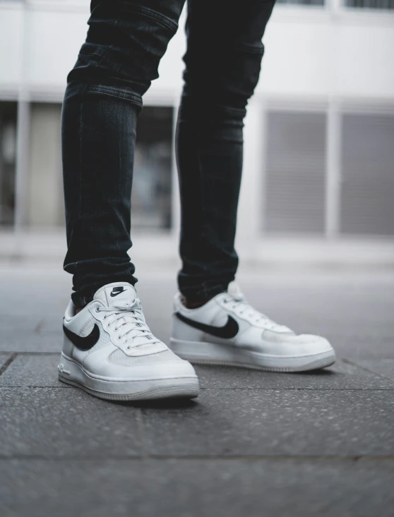 a man in white sneakers is standing on the street