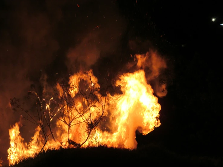 a large fire is being lit by several people in the night